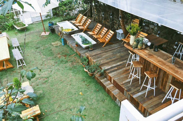 Quầy bar ngoài hiên, thảm cỏ xanh, bàn ghế gỗ, những chiếc ô trắng tạo nên một studio ngoài trời xinh xắn. Chỉ cần ngồi sưởi nắng trong không gian này cũng đủ khiến bạn khó quên. Ảnh: alazycatwanders