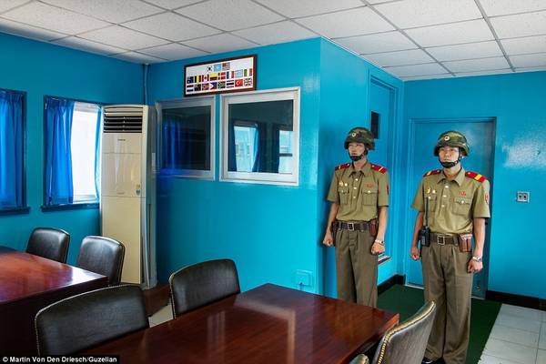 Hai người lính Quân đội Nhân dân Triều Tiên (KPA) đứng gác trong một phòng họp tại Khu vực An ninh Chung (JSA), phía trước cánh cửa dẫn sang Hàn Quốc.