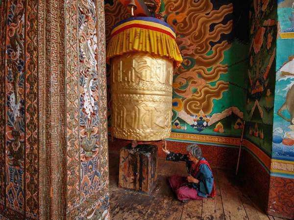 Bao quanh là những bức tranh Phật giáo đầy màu sắc, một cụ già quay kinh luân (bánh xe cầu nguyện) ở ngôi đền tại Punakha, phía tây Bhutan. Các kinh luân được chạm trổ tỉ mỉ với hàng nghìn câu thần chú. Người địa phương cho rằng quay bánh xe cũng như đọc những thần chú này hàng nghìn lần.