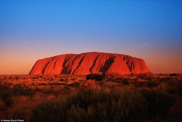 Núi Ayers đỏ rực trong ánh hoàng hôn, nổi bật trên nền trời vùng Outback của Australia.