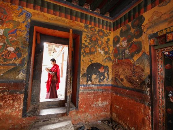 Nhà sư chỉnh sửa trang phục trước khi vào tu viện ở trung tâm Bhutan. Niềm tin Phật giáo có gốc rễ sâu xa là một trong những nhân tố chính để quốc gia này sử dụng GNP (tổng hạnh phúc quốc dân), thay cho GDP (tổng sản phẩm quốc nội) để đo độ thịnh vượng.