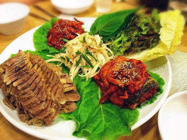 Bossam gồm thịt ba chỉ lợn luộc, cuốn trong lá tía tô cùng cải thảo và ăn kèm kimchi. 