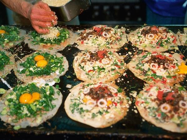 Okonomiyaki là món bánh xèo mặn, đặc sản của vùng Osaka và Hiroshima. Bên trên bánh được cho thêm nhiều thành phần khác nhau tùy theo vùng miền nhưng luôn có nước dùng dashi, trứng, cải xắt mỏng và thịt. 