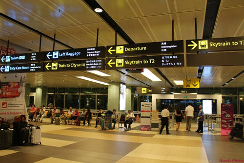 Sau khi ra khỏi khu vực thủ tục nhập cảnh Singapore tại Nhà ga số 1 của sân bay Changi, bạn rẽ trái theo hướng mũi tên chỉ dẫn Skytrain to T2 để đón tàu điện miễn phí từ Nhà ga số 1 sang Nhà ga số 2, vì trạm tàu điện ngầm đi vào trung tâm tọa lạc ở Nhà ga số 2.