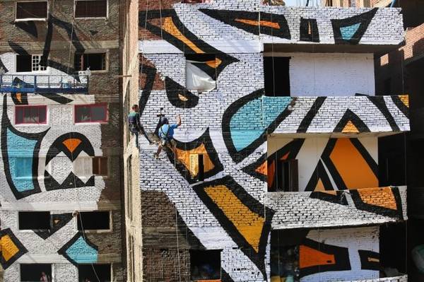  Một nhóm nghệ nhân đang thực hiện một phần tranh tường tại các tòa nhà trong khu phố rác - Ảnh: wp
