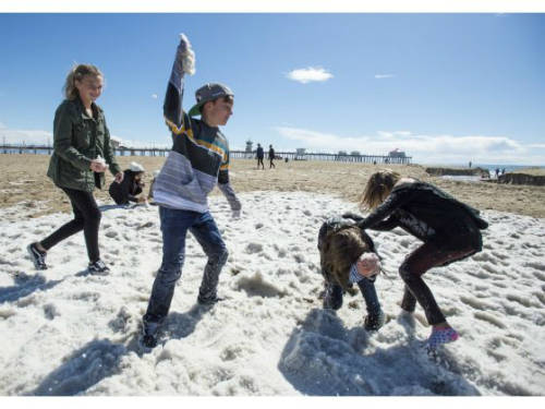 Trẻ em chơi đùa trên bãi biển Huntington trắng xóa sau trận mưa đá.