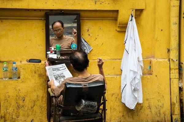 Một mảng màu bình dị trong cuộc sống thường nhật ở thủ đô Hà Nội: người thợ cắt tóc chăm chú đọc báo trong lúc chờ khách hàng.