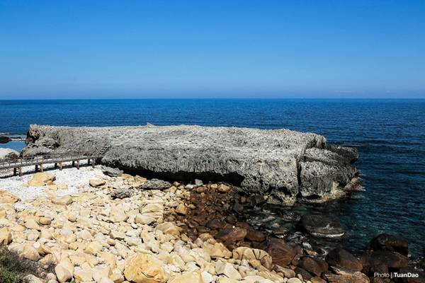 Nhìn từ xa, vách đá xù xì, hiểm trở trông như một phi thuyền khổng lồ, nổi bật trong nền nước biển xanh thẳm.