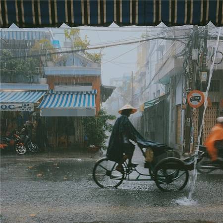 Sài Gòn mưa, những người lao động bé nhỏ vẫn xé màn mưa mà đi. (Ảnh: Âu Dương Thành)