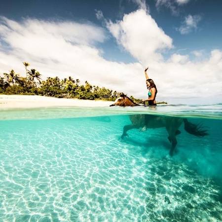 Thật thích khi được cưỡi ngựa trong làn nước xanh trong như pha lê và phía trên là bầu trời mênh mông tại Tonga. (Nguồn IG @perrinjames)