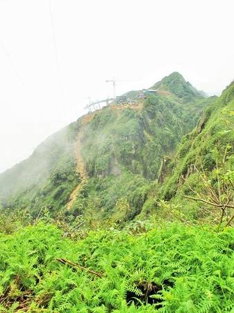 Đứng từ độ cao 2.900 m phóng tầm mắt ra phía trước có thể nhìn thấy đường mòn leo lên trạm xây dựng cáp treo và phía trên cùng chính là đỉnh Fansipan 3.143 m.