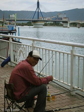 Một người đàn ông ngồi câu cá bên sông Hàn.