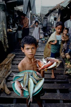 Chú bé bán cá tươi ở một khu chợ nghèo Philippines