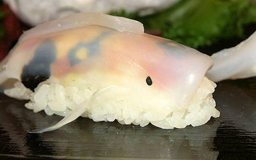 Lát mực thái mỏng theo hình cá đóng vai trò chủ chốt trong việc mang đến dáng hình sinh động cho miếng sushi. Sau cùng, rong biển được cắt nhỏ làm thành mắt.