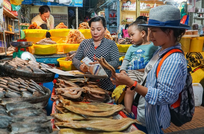 Chị Kim Ngân (phải), đến từ Hà Nội, ghé chơi chợ Châu Đốc trong chuyến du lịch miền Tây. "Các loại mắm và khô ở chợ rất phong phú, trình bày bắt mắt và rẻ hơn nơi khác", chị Ngân nói khi đang chọn mua khô cá về làm quà.