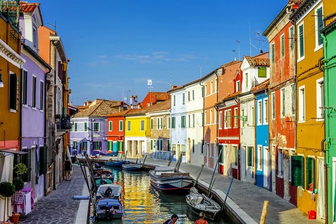 Đảo Burano, Italy Hòn đảo nhỏ ngoài khơi thành phố Venice được ví như viên ngọc giữa biển khơi. Mỗi ngôi nhà có một sắc màu riêng độc đáo. Do ngư dân không thể nhận ra nhà mình giữa lúc rạng đông sương mờ nên đã sơn nhà bằng nhiều màu. Ngày nay, nếu muốn sơn lại nhà, họ phải xin phép chính quyền và chỉ sơn một số màu chỉ định. Du khách đến đây có thể leo lên thuyền để đi dọc dòng kênh xanh biếc, ngắm nhìn hình ảnh phản chiều của dãy nhà sặc sở ở hai bên bờ. Đảo khá nhỏ lại yên tĩnh, ít hàng quán nên rất hợp cho những tâm hồn thơ mộng. Ảnh: Shutterstock/Alexandra Lande.
