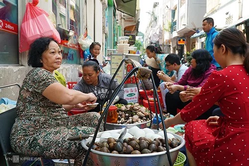 Bà Giang (ngoài cùng, bên trái) bán ốc luộc gần 20 năm tại Sài Gòn. Ảnh: Di Vỹ.