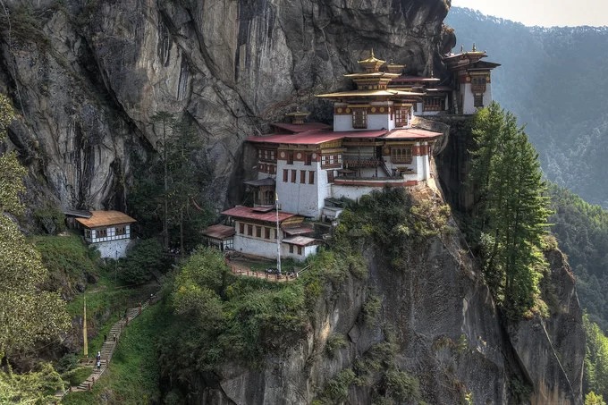 Bhutan có nhiều tu viện và công trình Phật giáo linh thiêng, nổi tiếng. Một trong số đó là tu viện Paro Taktsang xây dựng từ năm 1692, tọa lạc trên một vách đá cao giữa tầng mây nhìn xuống thung lũng Paro. Theo truyền thuyết, ngài Padmasambhava bay đến thung lũng Paro dưới hình dạng hóa thân của thần Dorji Drolo cưỡi trên lưng con hổ cái. Sau đó, ngài đã ngồi thiền suốt ba năm liên tục vào thế kỷ thứ 8 tại 13 hang động, trong đó Paro Taktsang là hang nổi tiếng nhất, nên người dân địa phương còn gọi hang này là Hang Hổ (Tiger Nest). Trên đường dẫn lên tu viện Paro Taktsang, du khách sẽ nhìn thấy làng Lakhang và chùa Urgyan Tsemo tọa lạc trên một khu núi đá khá bằng phẳng. Dọc lối mòn dẫn lên tu viện còn có một thác nước 60 m và đổ vào một hồ thiêng, cuối đường là chính điện của tu viện. Ảnh: Ruminate.