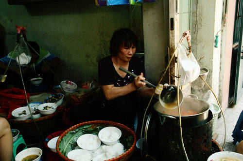 Bún ốc Hàng Chai Ghánh bún ốc ba thế hệ của cô Thêm là địa chỉ ẩm thực nổi tiếng khu phố cổ. Chuyện xếp hàng 15-20 phút để đến lượt ăn bát bún ốc rất bình thường. Điều đặc trưng của tô bún Hàng Chai là chỉ gồm có bún, ốc và vài gia vị đi kèm như hành lá, cà chua. Nước dùng trong vắt, có phần chua hơn so với bún ốc khác nhưng vẫn rất thanh, đậm đà và vừa miệng. Ảnh: Phong Vinh.