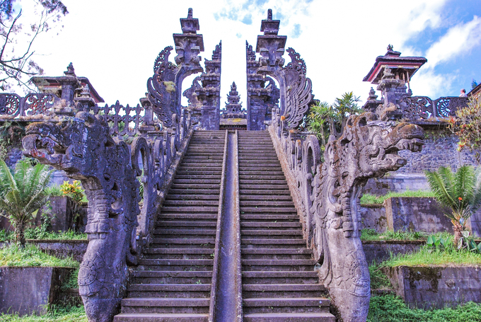 Cổng Candi Bentar là kiến trúc truyền thống của người Bali được xây dựng ở các đền thờ, nhà ở, cung điện hay nghĩa trang. Cánh cổng bao gồm hai nửa đồng dạng, đối xứng và được đặt hai bên lối vào. Khác với những kiến trúc thông thường, Candi Bentar không hề có điểm kết nối mà hoàn toàn là hai nửa tách biệt, mở ra một lối đi ở trung tâm. Ảnh: Bali Tour.