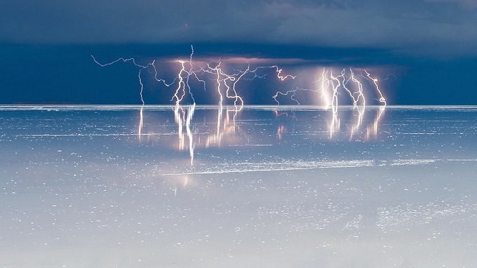 Trong những tháng mùa mưa ở tây nam Bolivia, làn nước mỏng đã biến Salar de Uyuni thành một tấm gương khổng lồ, phản chiếu bầu trời, chim hồng hạc, xe hơi và cả con người. Khí hậu ở đây rất khắc nghiệt, vào ban đêm trời lạnh buốt, có gió lớn và lượng mưa chỉ đạt mức 400 mm mỗi năm. Ảnh: Salar Andino.