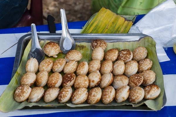 Khao Nom Krok trông như bánh căn Việt Nam, làm từ sữa dừa, đường, gạo nếp và bột mì. Ở miền Nam, món này ăn kèm với thịt heo băm nhỏ, chấm nước mắm chua ngọt - Ảnh: Matt Davies
