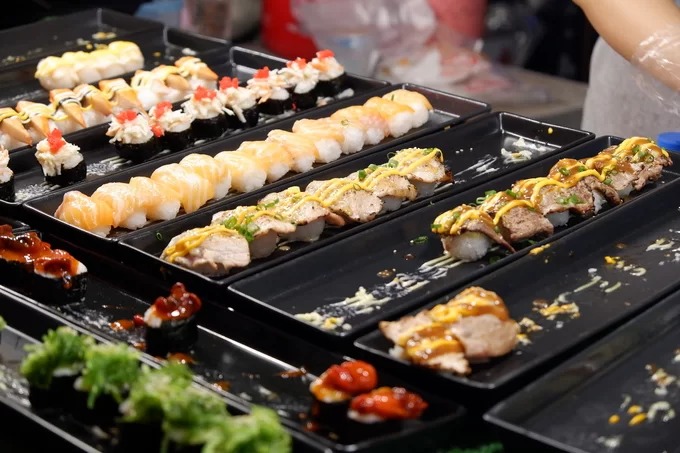 Cơm cuộn và sushi Không chỉ có các món Thái, những khu chợ ẩm thực Chiang Mai còn bán kèm đồ ăn theo phong cách Nhật, Hàn. Bên cạnh cá, bạch tuộc, trứng tôm và xoài, các quầy hàng còn bán thêm sushi thịt nướng, sushi bò. Mỗi set giá từ 40 đến 90 baht (30.000 - 70.000 đồng) tùy loại nhân ăn kèm.