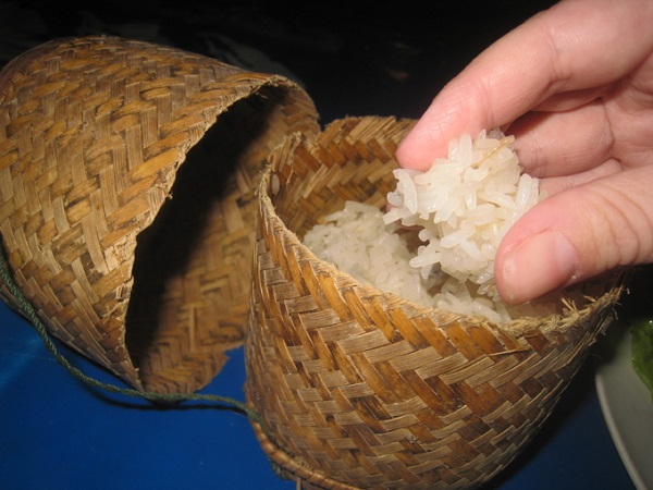 Khao Niaw (Xôi) nấu từ gạo dẻo, màu trắng ngà là món không thể thiếu trong tất cả các bữa ăn ở đây. Xôi được đựng trong một giỏ nhỏ đan bằng tre đơn giản, mộc mạc. Ăn đúng kiểu Lào là phải dùng tay nén thành viên tròn rồi mới cho vào miệng - Ảnh: mmmgoodfood