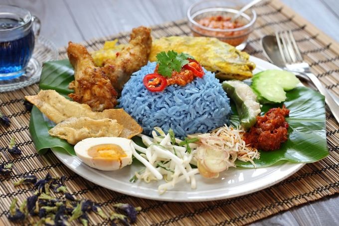 Nasi kerabu Cơm được nấu từ gạo màu xanh hay còn gọi là gạo thảo mộc. Sau khi nấu chín, cơm thường được ăn kèm cùng trứng muối, nước sốt, cá hồi chiên giòn, gà rán. Một suất thường được bán với giá khoảng 9 RM (50.000 đồng). Bạn có thể thưởng thức nasi kerabu ở nhà hàng Nasi kerabu Keramat hay Nasi kerabu Kambing Barkar ở thủ đô Malaysia. Ảnh: Shutterstock/Bonchan.