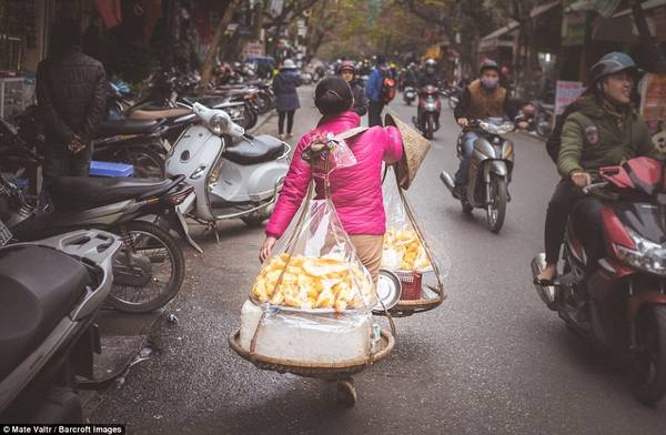 Một người bán rong gánh hàng đi trên phố. 