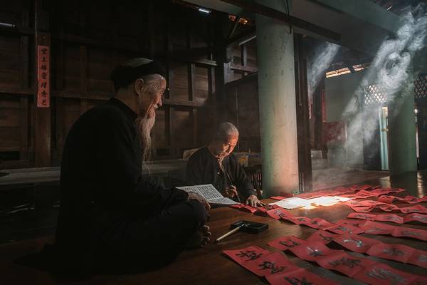 Hai cụ ông trong trang phục truyền thống ở Long Sơn (Bà Rịa - Vũng Tàu) viết câu đối để chuẩn bị đón năm mới. Ảnh: JetHuynh/Picfair.
