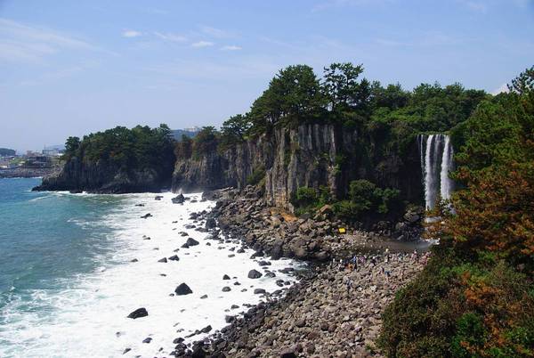 Thác nước Jeongbang: Đây là một trong 3 thác nước đẹp nhất Jeju - nơi duy nhất ở Hàn Quốc bạn có thể nhìn thấy nước đổ trực tiếp xuống biển. Trải nghiệm nên thử là ngồi trên các tảng đá và thưởng thức hải sản tươi ngon do dân địa phương đánh bắt. Ảnh: Trazy.co