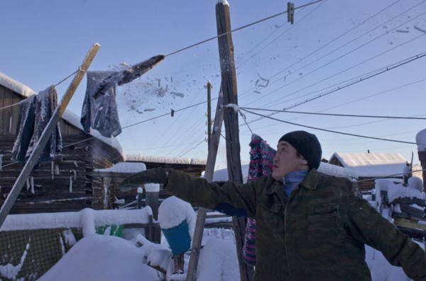 Người đàn ông gõ những băng tuyết đóng cứng trên dây điện - Ảnh: Daily Mail